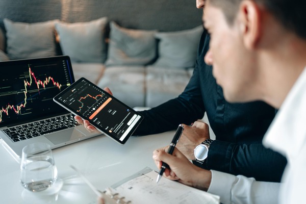 Analyst reviewing cryptocurrency price charts on a laptop and phone