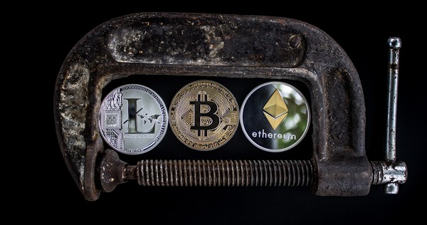 Padlock clamp securing Bitcoin, Litecoin and Ethereum coins